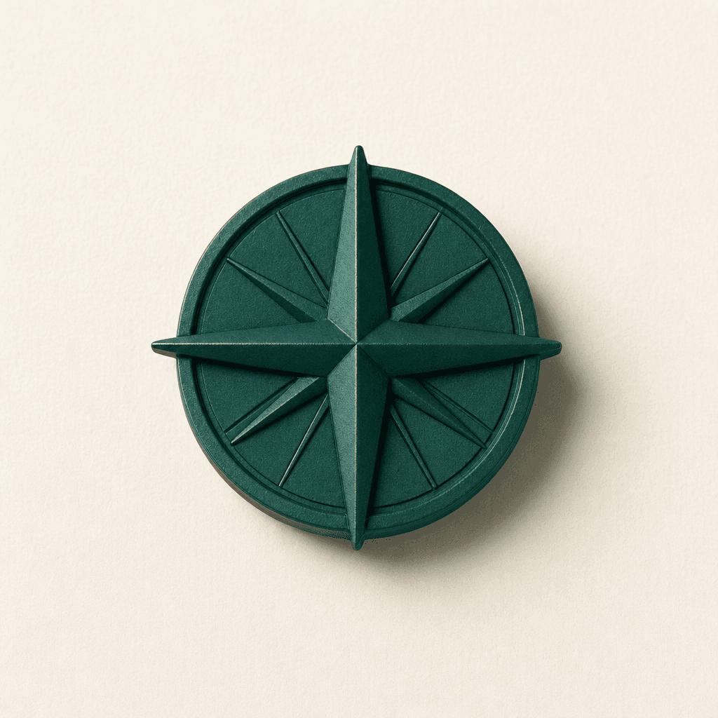 A small cast-bronze compass rose finished in matte deep teal, lying flat on a cream paper surface — a marker of where data belongs.